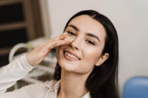 Girl smiling and touching her nose after rhinoplasty